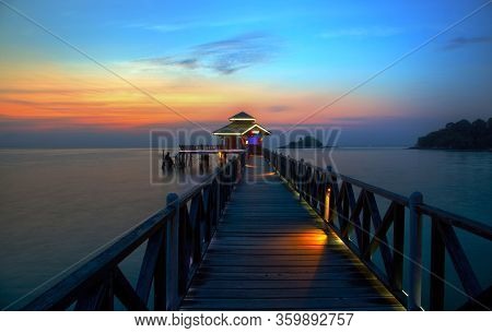 Romantic Tropical Lagoon Sunset On Bintan Island In Indonesia With Silhouette Of A Boat Jetty Hut.