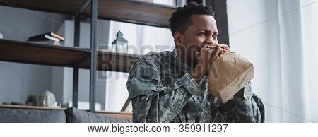 Panoramic Shot Of African American Soldier In Military Uniform Breathing With Paper Bag While Having