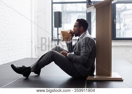 Nervous African American Speaker Breathing With Paper Bag And Having Panic Attack During Business Co
