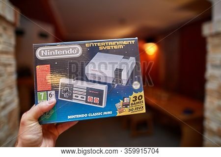 BUDAPEST, HUNGARY - DECEMBER 10, 2017: Nintendo NES classic edition video game console, box geld in hand. Modernized version of the original with preinstalled games