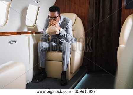 Nervous African American Businessman Breathing With Paper Bag While Having Panic Attack During Fligh