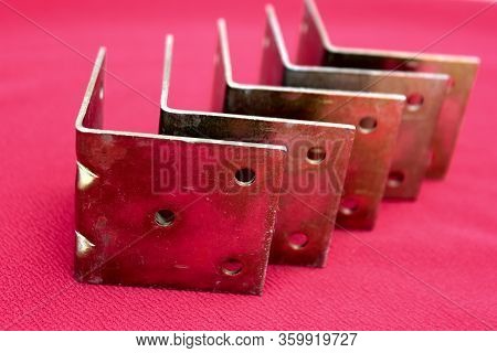 Arrow Made Of Brackets Isolated On Pink. Metal Corners Pointing Down With A Place For The Text. Gold