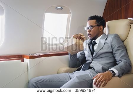 Worried African American Businessman Breathing With Paper Bag While Having Panic Attack During Fligh