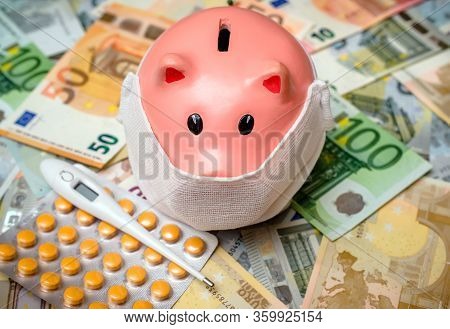Piggy Bank In A Mask On A Background Of European Currency.the Concept Of Coronavrius Epidemic