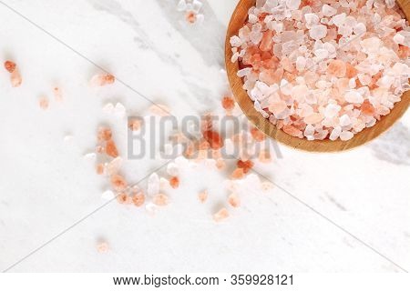 Top View Of Himalayan Pink Rock Salt In Wooden Bowl On White Marble Table With Copy Space.