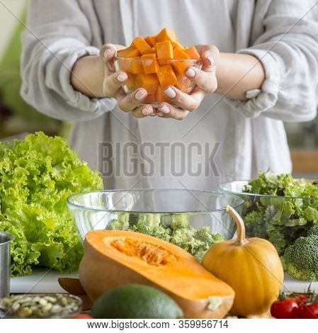 Unrecognizable Girl Enjoying Vegetable Salad With Pumpkin In Glass Bowl Over Kitchen Background
