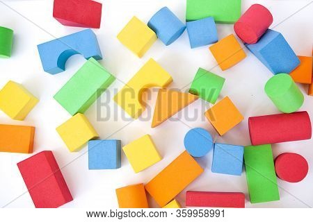 A Child Builds A Pyramid Of Cubes On A White Background. The Boy's Hand Holds A Cube.