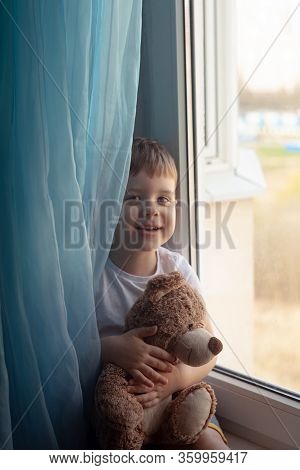 Stay At Home Quarantine Coronavirus Prevention Of The Pandemic. A Child And His Teddy Bear On The Wi