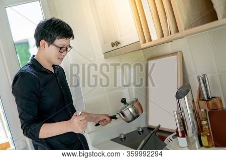 Asian Man Watching Cooking Tutorial On Digital Tablet Learning How To Cook Food In The Kitchen. Dome