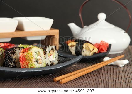 Velsmagende Maki sushi - Roll på grønne blade på bordet på grå baggrund