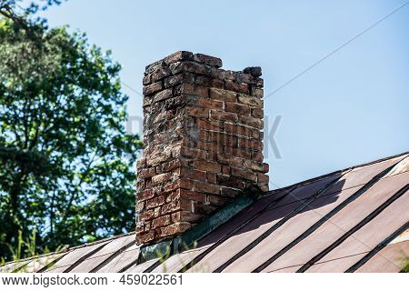 Old Brick Chimney In Need Of Repair On A Roof. Heating And Fire Safety Concept