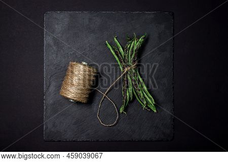 String Beans On A Black Background. A Bunch Of Raw Green Beans Tied With A Rope. Healthy Vegetable