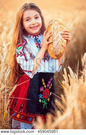 Beautiful Girl Woman In Traditional Bulgarian Folklore Dress Holding Homemade Bread In Wheat Field