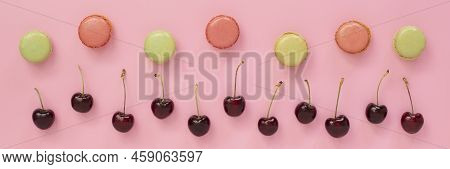 Red Cherries And Lime And Coral Colored Macarons Closeup Top View On Pink Background. Decorative Ban