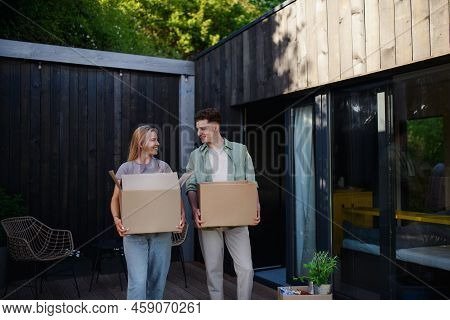 Cheerful Young Couple Moving In Their New Tiny House In Woods. Conception Of Moving And Sustainable 