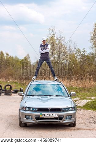 Lviv Ukraine - 05 02 2022: A Young Man In Stylish Clothes And A Cap Stands On The Roof Of A Mitsubis
