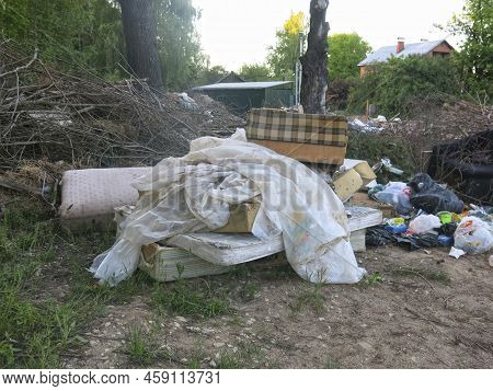 Garbage From Human Activity Lies In A Rural Garbage Dump: Boards, Furniture, Branches, Bags