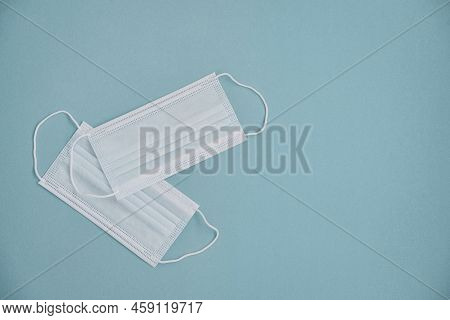 Tipical Surgical Masks With Rubber Ear Straps On Blue Background, Top View . Protection Concept.