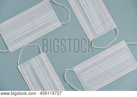 Tipical Surgical Masks With Rubber Ear Straps On Blue Background, Top View . Protection Concept.