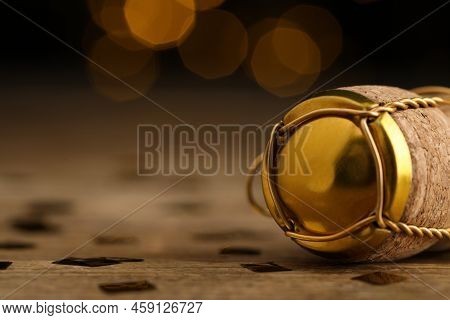 Closeup View Of Sparkling Wine Cork And Muselet Cap On Wooden Table Against Blurred Festive Lights, 