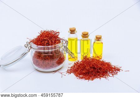 Glass Jar Filled With Red Saffron Stamens And Pile Of Red Stamens.