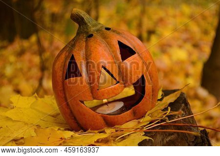 Pumpkins Candles On Golden Leaves In Autumn Forest With Defocused Sunset Background. Halloween Holid