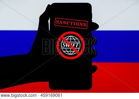 Ukraine, Kiev - February, 23 2022: Silhouette Of Black Hand Holding Mobile With Crossed Out Swift Lo