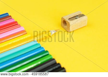 Set Of Colored Pencils And A Sharpener On A Bright Yellow Background. One Pencil In The Center Is Pu