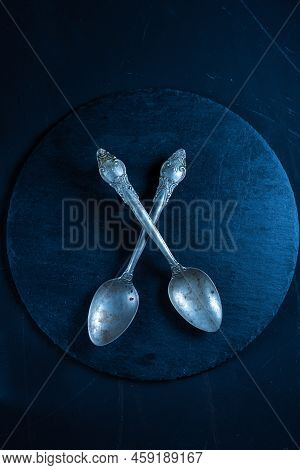 Two Old Spoons On A Slate Board. Cupronickel Teaspoons On The Table. Silver Vintage Spoons. Vertical