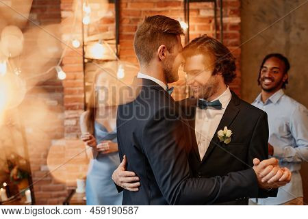 Dreamy Portrait Of Young Gay Couple Dancing Together During Wedding Reception With Lens Flare