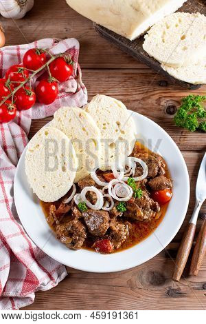 Beef Goulash With Bread Dumplings And Parsley Garnish On White Ceramic Plate On Wooden Table. Top Vi