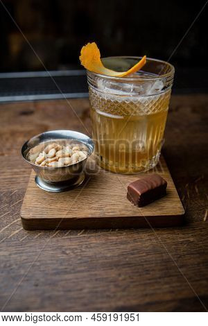 Alcoholic Cocktail With Peanuts And Candy On A Wooden Table