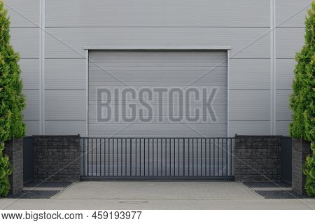 Gate Or Roller Shutter With Application To Factory, Warehouse Or Hangar. Outside, Trees On The Sides