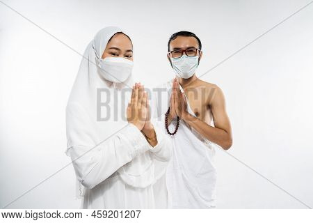Asian Couple Wearing Ihram Clothes And Mask With Salam Gesture