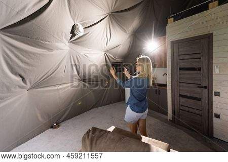 Woman With Tablet Turning On Ventilation System As A Recuperator For Fresh Indoor Air Quality, Smart