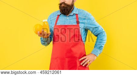 Man Crop View In Apron Holding Orange And Juice Bottle Yellow Background, Juicery