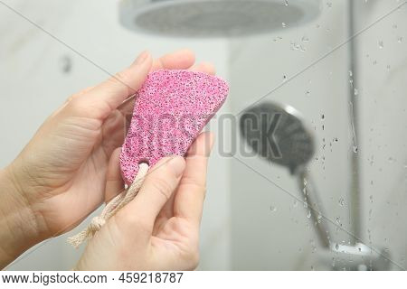Woman Holding Pink Pumice Stone Near Shower Stall In Bathroom, Closeup. Space For Text