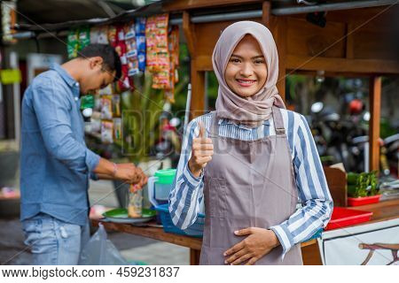 Woman Standing In Front Of Her Small Traditional Food Shop And Showing Thumb Up