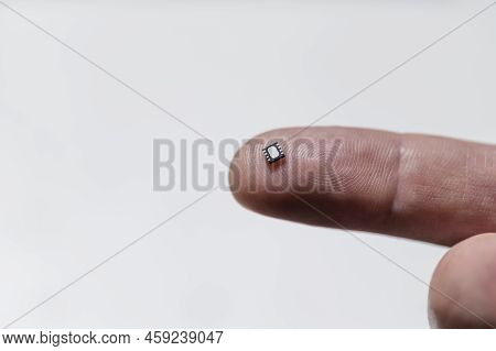 Close Up Of Electronic Micro Chip On Human Finger.