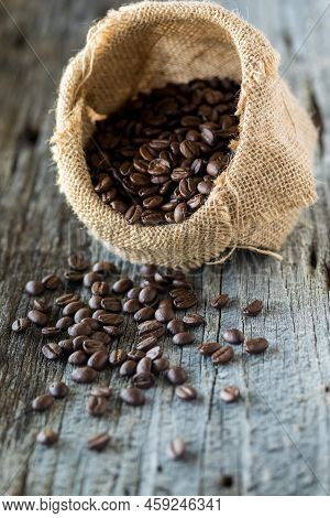 A Burlap Sack Filled With Coffee Beans And A Pile Spilled Out In Front.