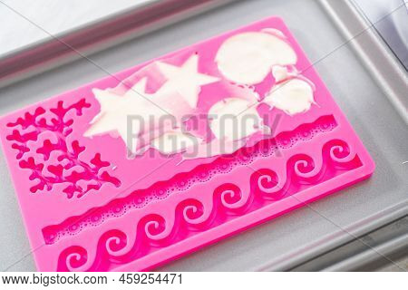 Filling Silicone Chocolate Molds With White Melted Chocolate To Prepare Mermaid Cakesicles.