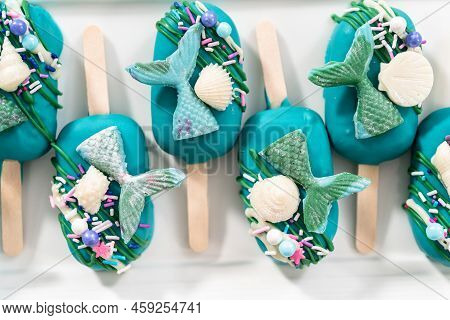 Mermaid Cakesicles With Drizzled Chocolate, Chocolate Mermaid Tails, Seashells, And Sprinkles.