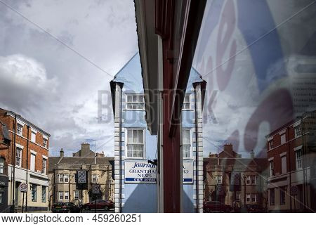 Grantham, Lincolnshire, England- August 2, 2022. Blue Tall Building With Window Reflections On Marke