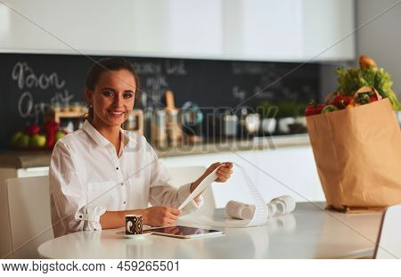 Young Woman Planning Expenses And Paying Bills On Her Kitchen