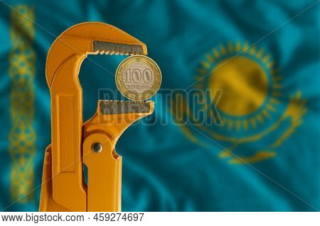 100 Kazakhstani Tenge Held In An Orange Plumber Wrench On The Background Of Kazakhstan Flag. Reverse