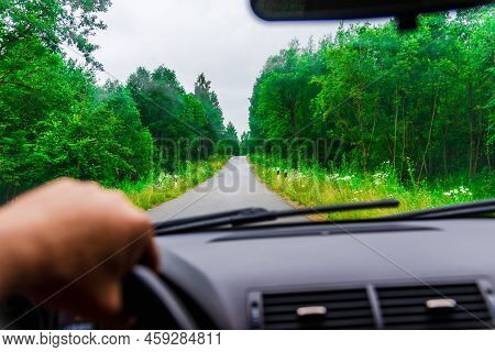 View Of The Road Through The Windshield Of The Car.driver\'s Hand On Steering Wheel At Forest Rainy 