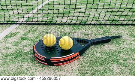 Yellow Balls Over Padel Tennis Racket Behind Net In Green Court Outdoors