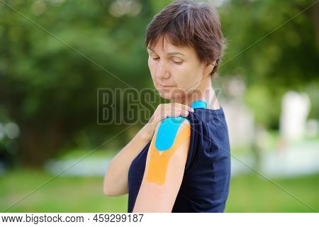 Woman With Kinesio Tape On Her Shoulder. Method Is Purported To Ease Pain And Disability From Athlet