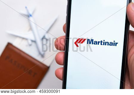 Martinair Airline Application On The Smartphone Screen Mans Hand. A White Toy Airplane And A Passpor