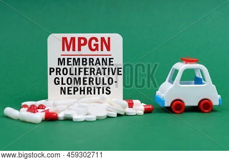 Medical Concept. On A Green Surface, An Ambulance, Pills And A White Sign With The Inscription - Mem